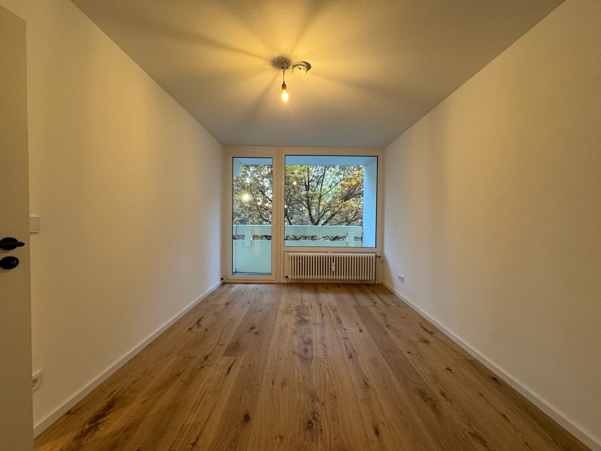 Nachher – Zimmer mit neuem Boden in Holzoptik und Balkontür